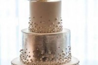 a glam white and silver wedding cake decorated with white and silver beads and a single magnolia bloom on top