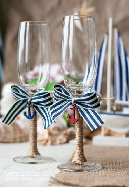 wedding flutes decorated with striped bows and wrapped with twine, with little colorful anchor pendants for a nautical wedding