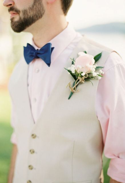 a delicate groom's look with a blush shirt, a neutral waistcoat, a navy bow tie and a blush bloom boutonniere accented with an anchor