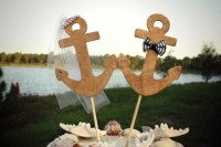 a neutral wedding cake topped with seashells and plywood anchors is a stylish solution for a seaside or nautical wedding