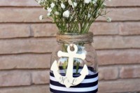 a wedding centerpiece of a jar with a striped ribbon, an anchor, baby’s breath is a lovely decoration for a modern wedding