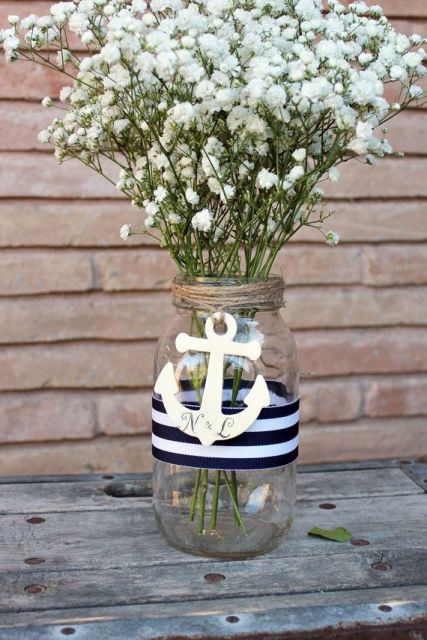 a wedding centerpiece of a jar with a striped ribbon, an anchor, baby's breath is a lovely decoration for a modern wedding