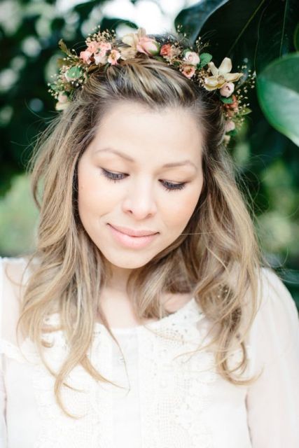 a delicate pastel floral crown with greenery attached on top the hairstyle as a tiara is a chic and pretty idea that will bring a cute touch