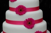 a round wedding cake with pink ribbon and pink gerberas is a cool and bold idea for a spring or summer wedding