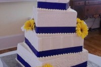 a white square wedding cake with navy ribbon and bold yellow gerberas is a lovely idea for a colorful or contrasting wedding