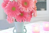 a bright wedding centerpiece of a blue vase and pink gerberas is a lovely idea for a spring or summer wedding with plenty of color