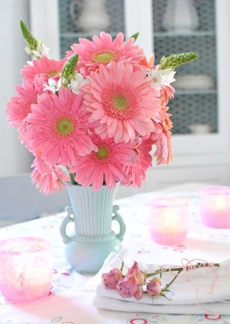 a bright wedding centerpiece of a blue vase and pink gerberas is a lovely idea for a spring or summer wedding with plenty of color