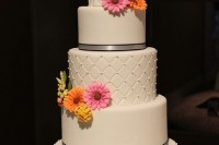 a white wedding cake with silver ribbon and colorful gerberas is a lovely idea for a spring or summer wedding