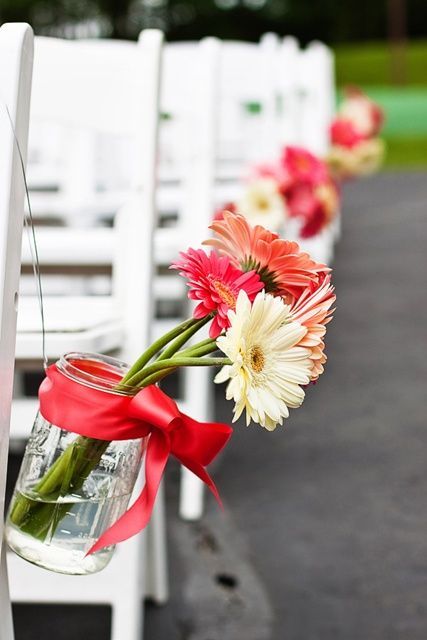 a bold aisle decoration of white, orange and red gerberas and a bold red ribbon is a lovely idea for a bold aisle at the wedding