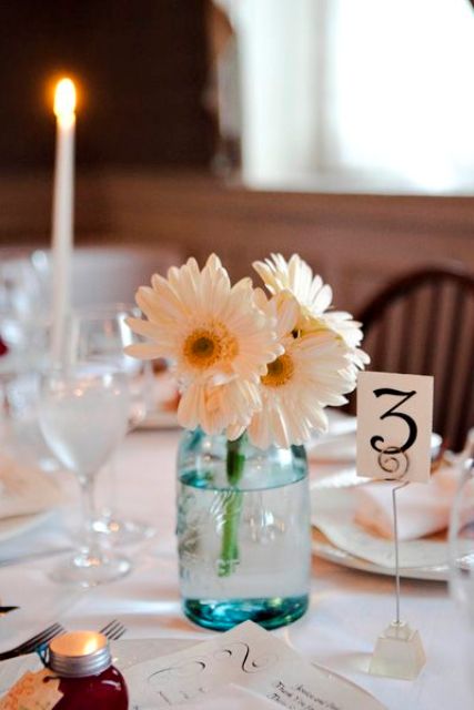 a chic and simple neutral wedding centerpiece of a blue jar and white gerberas is a lovely idea for a rustic wedding
