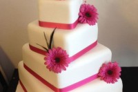a catchy irregular square wedding cake with pink ribbon and pink gerberas is a lovely idea for a spring or summer wedding