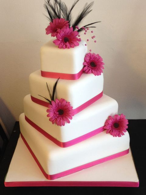 a catchy irregular square wedding cake with pink ribbon and pink gerberas is a lovely idea for a spring or summer wedding