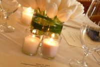 a wedding centerpiece composed of white tulips and white candles is an elegant and timeless idea to try for your wedding