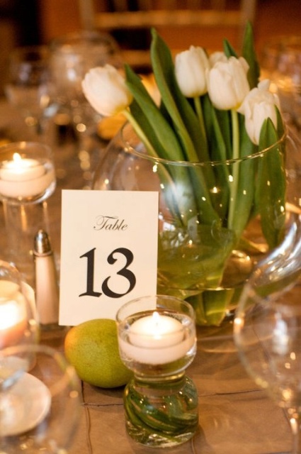 a spring wedding centerpiece of white tulips, candles and a table number is a cool idea for a spring or summer wedding