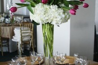 a tall wedding centerpiece of a clear vase with purple tulips and white hydrangeas is a lovely idea for spring or summer