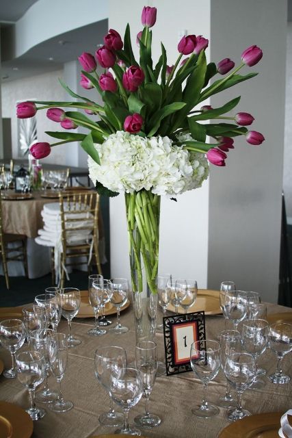 a tall wedding centerpiece of a clear vase with purple tulips and white hydrangeas is a lovely idea for spring or summer