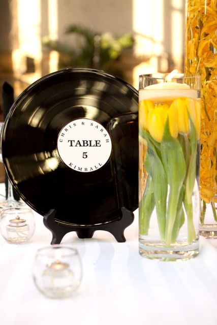 a wedding centerpiece composed of yellow tulips and a vinyl piece with a table number for a retro wedding