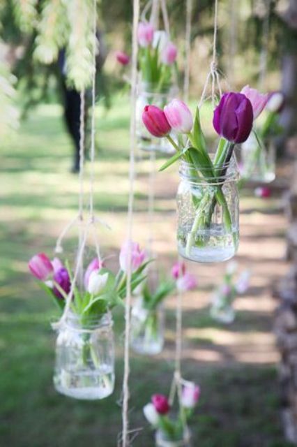 lovely rustic wedding decor of jars suspended with some pink tulips are amazing to style your wedding decor, both indoors and outdoors