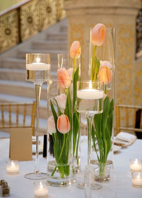 a chic modern wedding centerpiece of tall glass vases, peachy tulips, floating candles around is a chic and stylish idea to rock