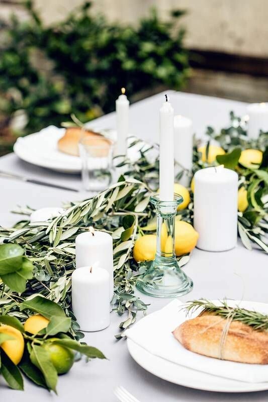 a Tuscan wedding tablescape with a lush greenery table runner and lemons, pillar and tall and thin candles is awesome
