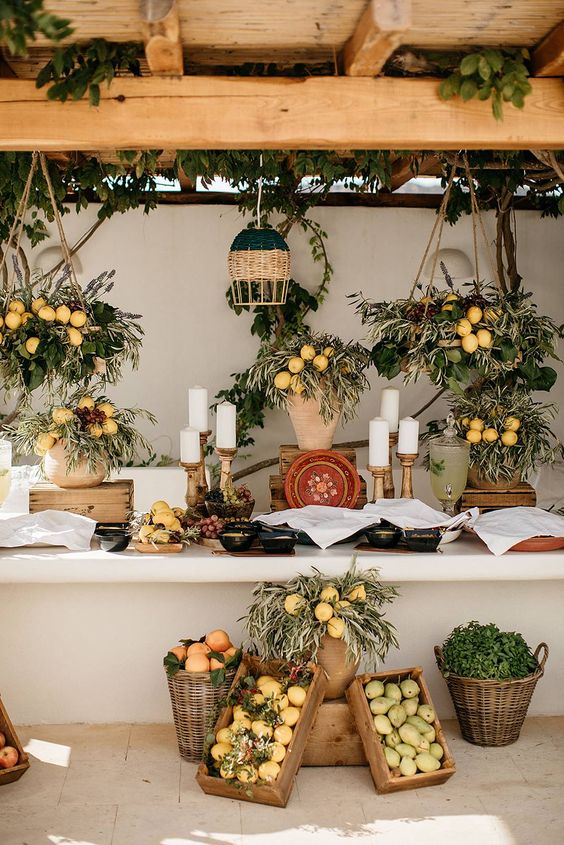 a beautiful rustic wedding station with greenery and lemon arrangements, pillar candles, crates and baskets with lemons all around