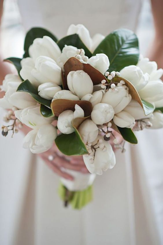a beautiful wedding bouquet of white tulips, magnolia leaves and berries is a lovely idea for a spring or summer wedding