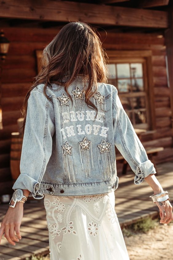 a bleached embellished and fringed bridal denim jacket with applique letters is a cool coverup for a boho bride