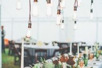 a boho wedding reception with greenery, foliage and green and amber glasses, a chandelier made of a living edge piece of wood and bulbs