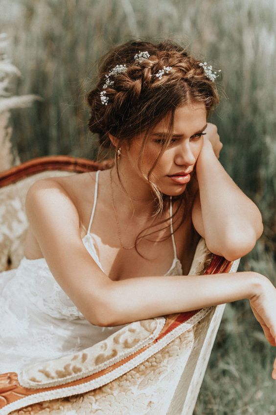 a boho wedding updo with a braided halo and some locks down plus baby's breath tucked in is a great idea for a boho spring bride