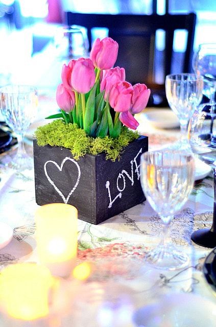 a bold rustic wedding centerpiece of a chalkboard box, moss and hot pink tulips is a great idea for a bold spring wedding