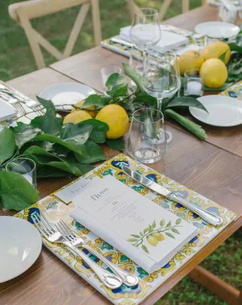a bold summer wedding tablescape with a greenery and lemon table runner, a bold placemat and printed menus is awesome