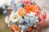 a bold wedding bouquet of blue hydrangeas, white blooms, orange gerberas and roses and some greenery