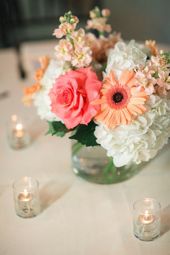 a bold wedding centerpiece of white hydrangeas, a pink rose and orange gerberas is a cool and bright decoration