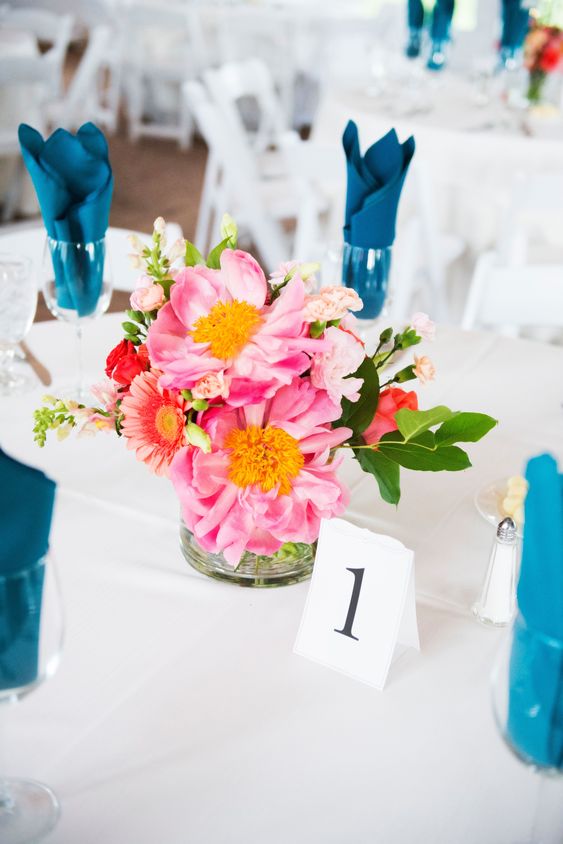 a bright and fun wedding centerpiece of pink poenies, coral roses and gerberas and greenery is amazing