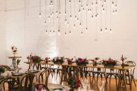a bright boho wedding reception with bold and jewel tone blooms and an installation with bulbs hanging down for a bolder look