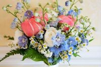 a bright wedding bouquet of white ranunculus, blue blooms and pink tulips plus greenery and chamomiles is awesome