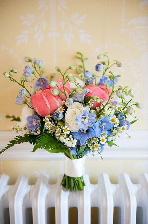 a bright wedding bouquet of white ranunculus, blue blooms and pink tulips plus greenery and chamomiles is awesome