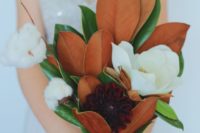 a chic wedding bouquet of magnolia blooms and leaves, burgundy blooms and cotton