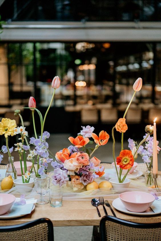 a colorful artful wedding centerpiece of various blooms in pastel and bright colors including tulips, daffodils and others
