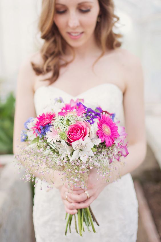 a colorful wedding bouquet of hot pink, purple, blue and neutral blooms and pink baby's breath is amazing