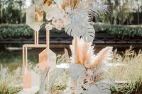 a creative botanical wedding backdrop of pampas grass, white monstera leaves, dried fronds and geometric details is wow
