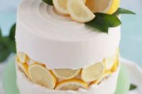a creative fault line wedding cake with white buttercream, cut lemons on top and greenery is a lovely idea for a summer wedding