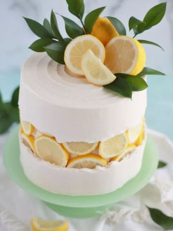 a creative fault line wedding cake with white buttercream, cut lemons on top and greenery is a lovely idea for a summer wedding