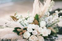 a dimensional and textural wedding centerpiece of blush roses, pampas grass and magnolia leaves