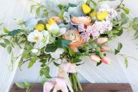 a dreamy pastel spring wedding bouquet of white and blush blooms, pink and yellow tulips, greenery and pale greenery and blush ribbons