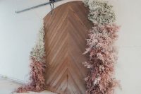 a gorgeous botanical wedding backdrop of a barn door and ombre grasses and baby’s breath is amazing