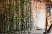 a hanging greenery backdrop with lights will soften the industrial space and make it look inspiring and fresh