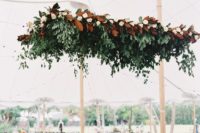 a large wedding decoration of greenery and magnolias is a cool way to accent your dance floor
