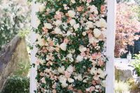 a lovely botanical wedding backdrop of white, blush blooms and greenery and foliage in a frame is a very refined and chic idea