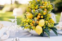 a lovely wedding centerpiece of mimosa blooms, lemons and kumquats and some foliage is a lovely idea of a summer decoration